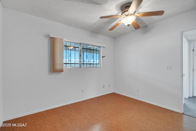 spare room with baseboards, ceiling fan, a textured ceiling, and wood finished floors