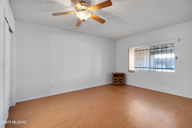 unfurnished room featuring baseboards, a textured ceiling, ceiling fan, and wood finished floors