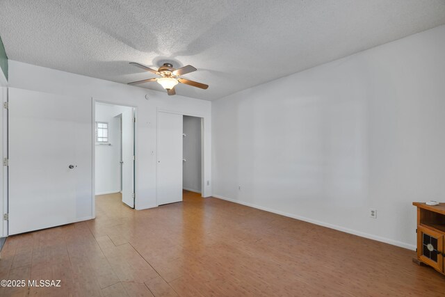 unfurnished bedroom featuring baseboards, a ceiling fan, a textured ceiling, and wood finished floors