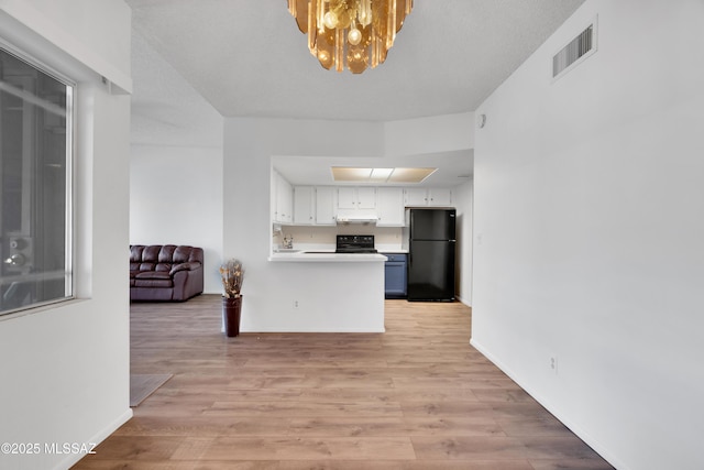 kitchen with visible vents, light countertops, under cabinet range hood, white cabinets, and black appliances