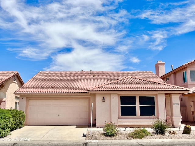 view of front facade with an attached garage, a tile roof, driveway, and stucco siding