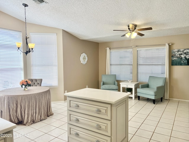 kitchen featuring light tile patterned floors, light countertops, a textured ceiling, and ceiling fan with notable chandelier