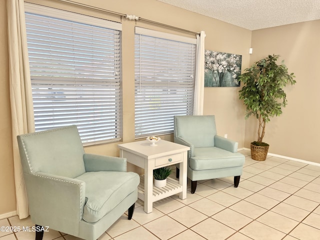 living area featuring baseboards, a textured ceiling, and light tile patterned floors