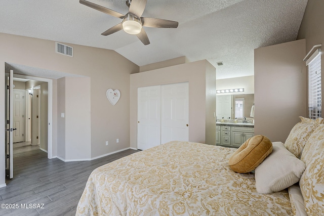 bedroom with vaulted ceiling, wood finished floors, visible vents, and baseboards