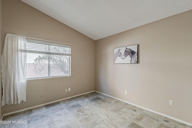 spare room with vaulted ceiling, a textured ceiling, and baseboards