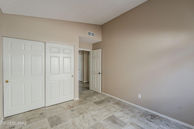 unfurnished bedroom with a closet, lofted ceiling, visible vents, and baseboards