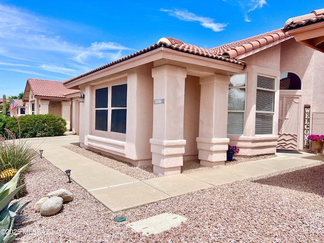 view of side of home with stucco siding and a tiled roof