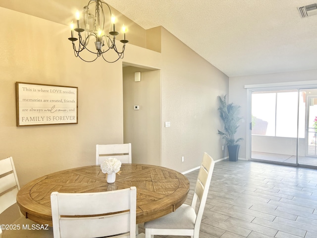 dining space with wood finished floors, a chandelier, baseboards, lofted ceiling, and visible vents