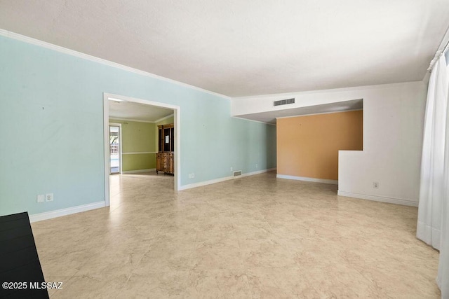 empty room featuring baseboards, ornamental molding, and visible vents