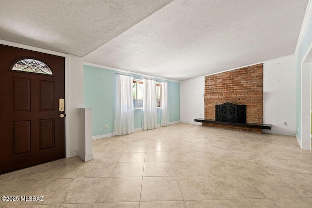 foyer entrance with light tile patterned flooring, a brick fireplace, a textured ceiling, baseboards, and ornamental molding