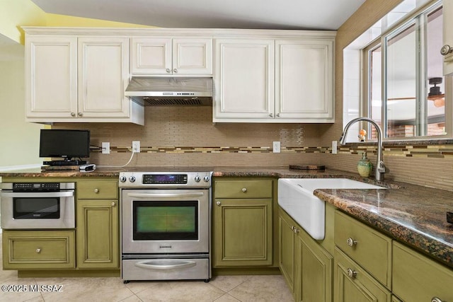kitchen with a sink, green cabinetry, under cabinet range hood, and stainless steel appliances