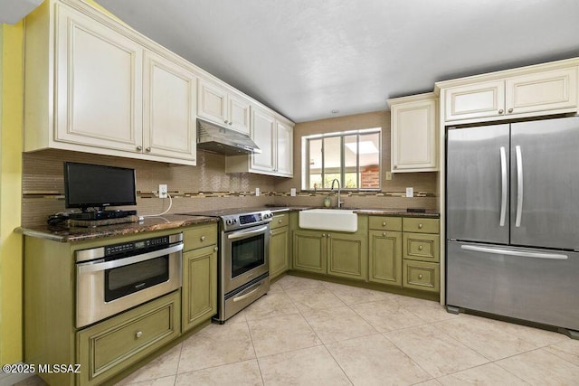kitchen featuring under cabinet range hood, stainless steel appliances, a sink, and green cabinets