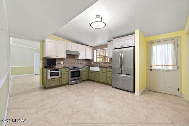 kitchen featuring baseboards, appliances with stainless steel finishes, under cabinet range hood, and vaulted ceiling