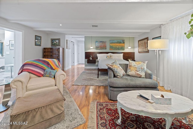 living area featuring visible vents, baseboards, wood finished floors, and beamed ceiling