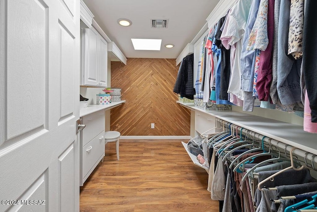 spacious closet featuring visible vents, light wood-style flooring, and a skylight