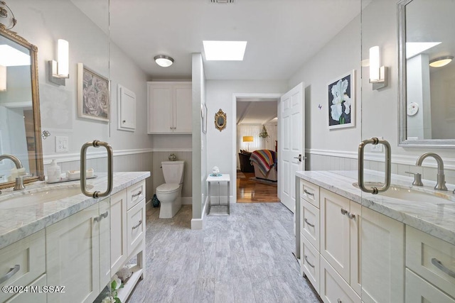 bathroom with a sink, a skylight, ensuite bathroom, and wood finished floors