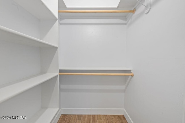 walk in closet with wood finished floors