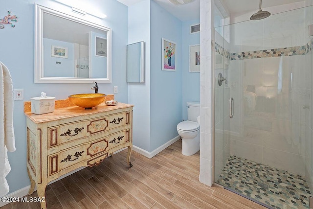 bathroom featuring visible vents, vanity, wood finished floors, toilet, and a shower stall