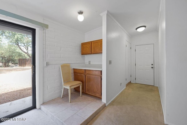 interior space with brown cabinetry, ornamental molding, light carpet, and light countertops
