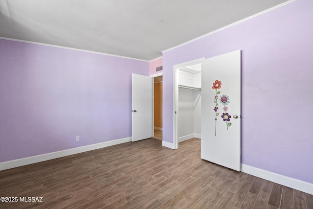 unfurnished bedroom featuring baseboards, visible vents, ornamental molding, and wood finished floors