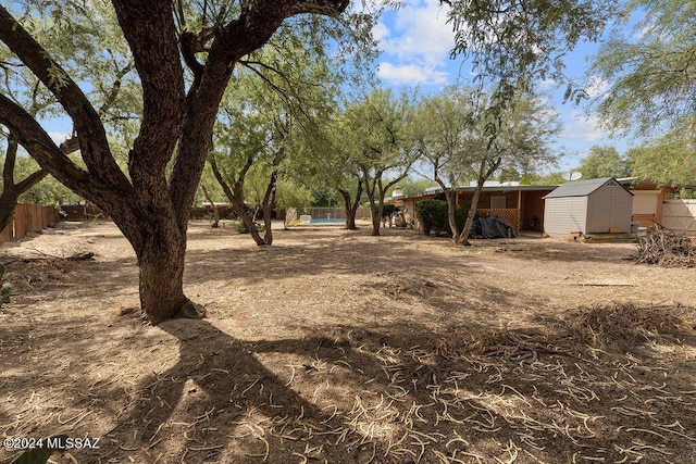 view of yard with fence, an outbuilding, and a shed