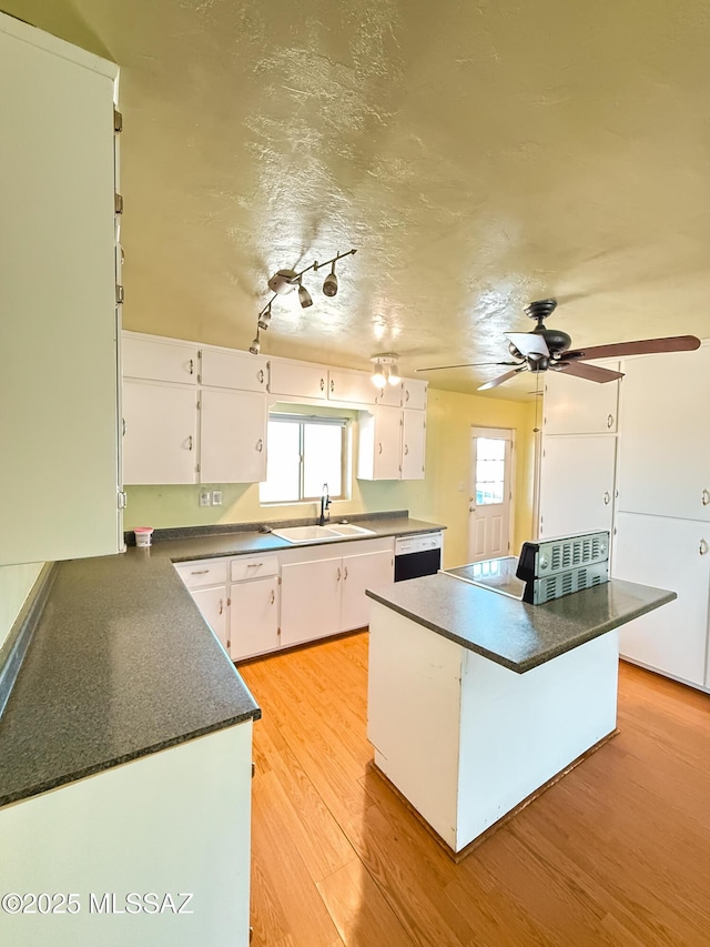 1350 E Goosetree Ln, Safford, AZ 85546 - kitchen featuring white cabinets, dark countertops, a sink, light wood-style floors, and a kitchen island