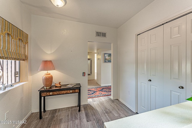 interior space featuring baseboards, a closet, wood finished floors, and visible vents