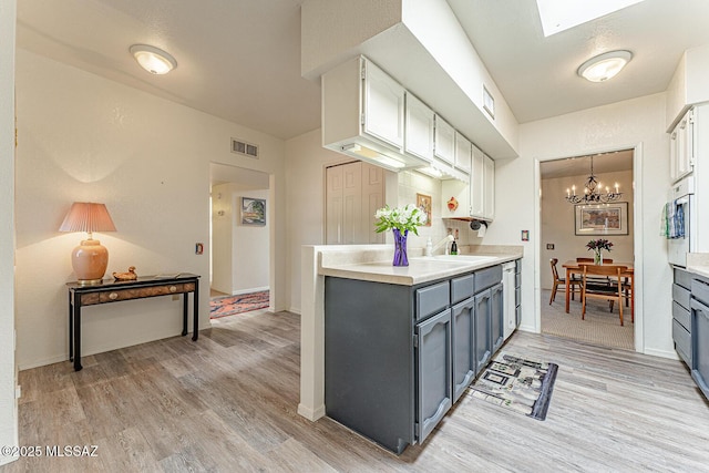 kitchen with visible vents, light countertops, light wood finished floors, and a notable chandelier