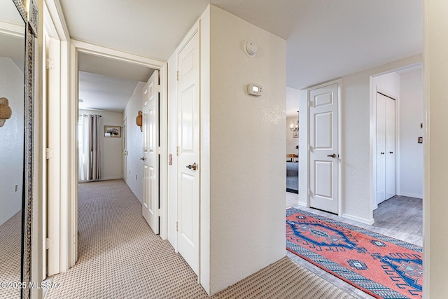 corridor with baseboards and carpet flooring