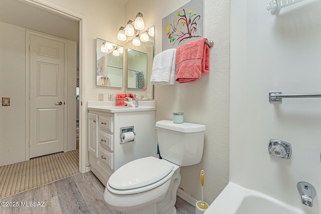 full bathroom with vanity, a tub to relax in, toilet, and wood finished floors