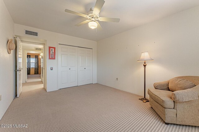 living area featuring visible vents, ceiling fan, and light carpet