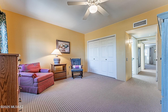 living area featuring carpet floors, ceiling fan, and visible vents