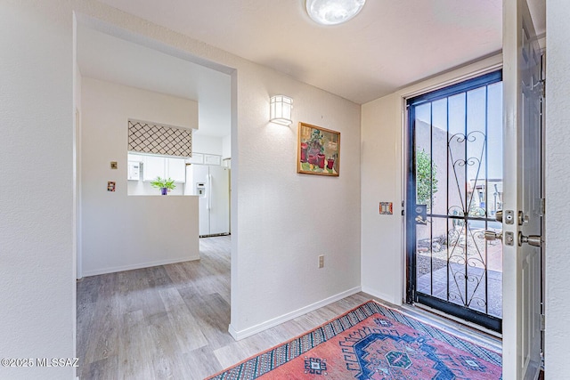 entrance foyer featuring baseboards, a textured wall, and wood finished floors