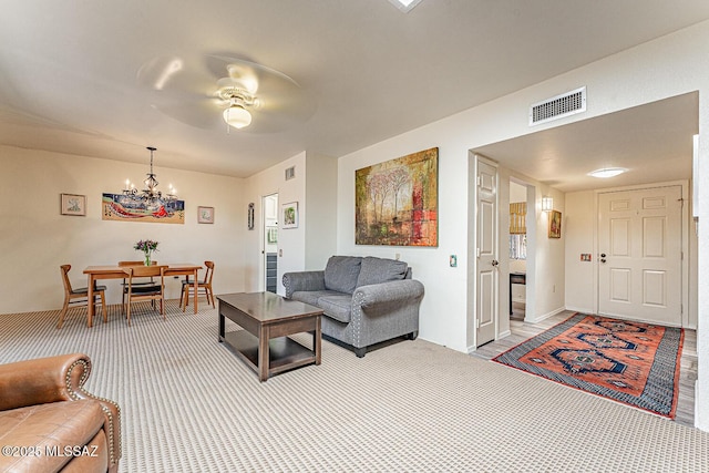 carpeted living room with visible vents and ceiling fan with notable chandelier