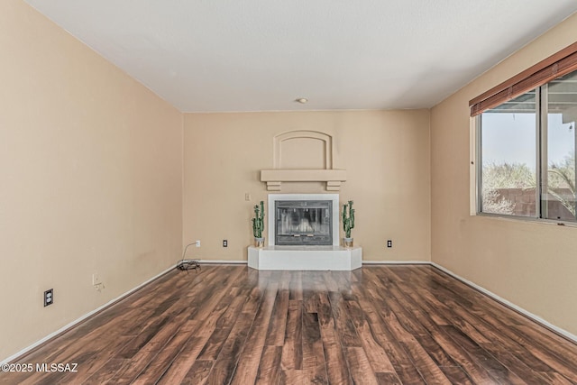 unfurnished living room featuring baseboards, a glass covered fireplace, and wood finished floors