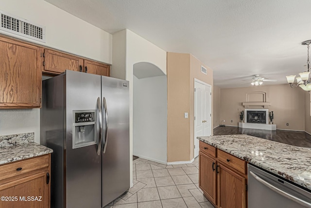 kitchen featuring appliances with stainless steel finishes, brown cabinetry, ceiling fan with notable chandelier, open floor plan, and visible vents