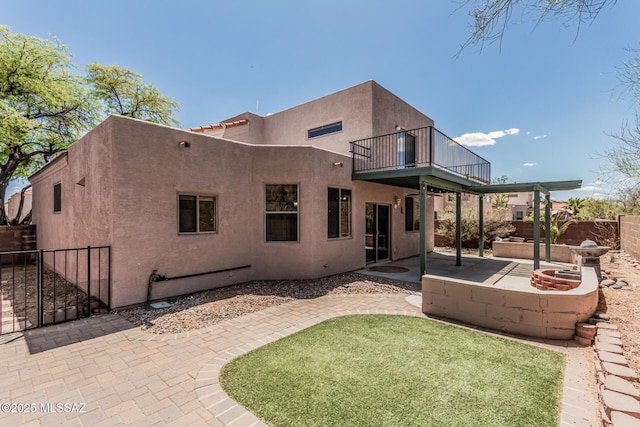 rear view of house featuring a lawn, a patio area, a balcony, a fenced backyard, and stucco siding