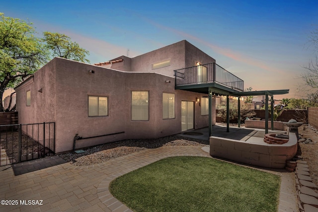 back of property with a fenced backyard, a patio area, stucco siding, and a balcony