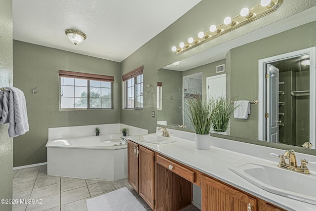 bathroom with a sink, a textured wall, a garden tub, and visible vents
