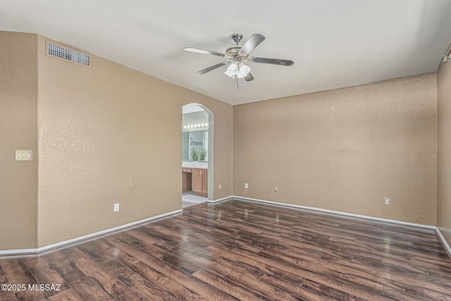spare room with ceiling fan, arched walkways, baseboards, wood finished floors, and visible vents