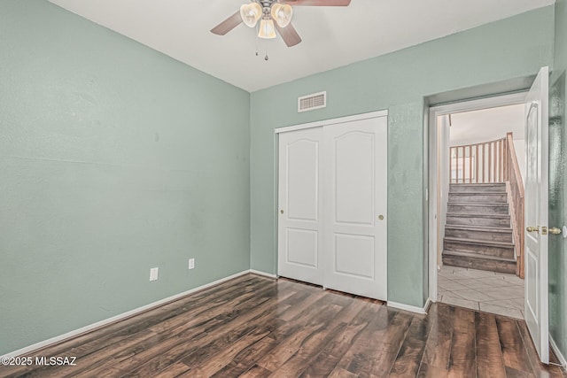 unfurnished bedroom featuring visible vents, a closet, wood finished floors, baseboards, and a ceiling fan