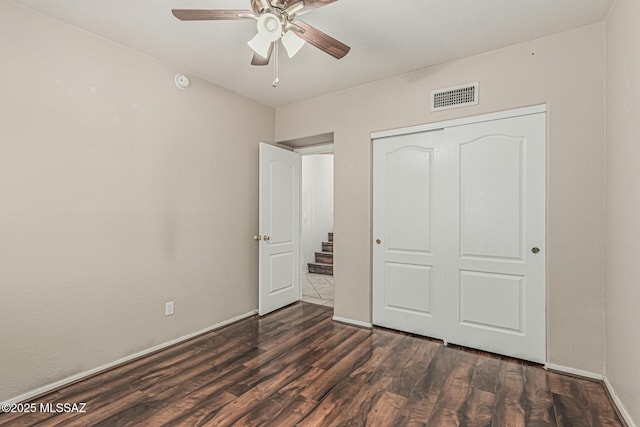unfurnished bedroom featuring a ceiling fan, visible vents, dark wood finished floors, baseboards, and a closet