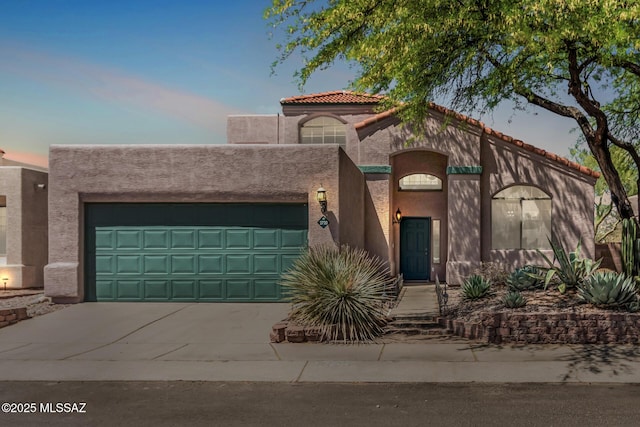 view of front of house with an attached garage, concrete driveway, and stucco siding