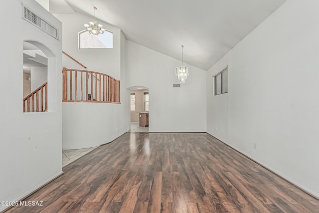 interior space featuring visible vents, arched walkways, wood finished floors, stairway, and a notable chandelier