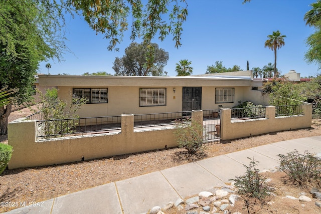ranch-style house with a gate, a fenced front yard, and stucco siding