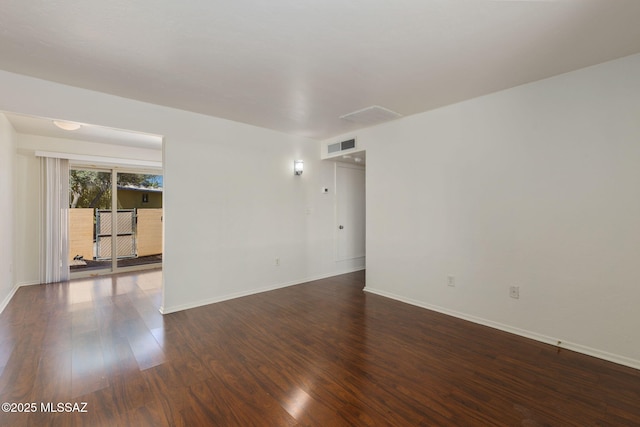 empty room featuring visible vents, dark wood finished floors, and baseboards