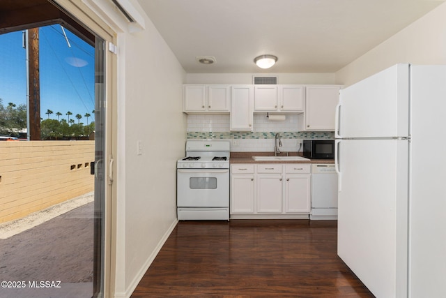 kitchen featuring white appliances, white cabinets, backsplash, a sink, and visible vents