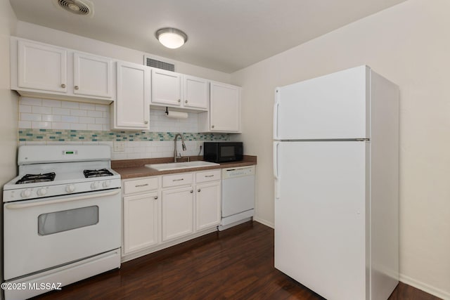 kitchen featuring a sink, visible vents, white appliances, white cabinets, and dark wood finished floors