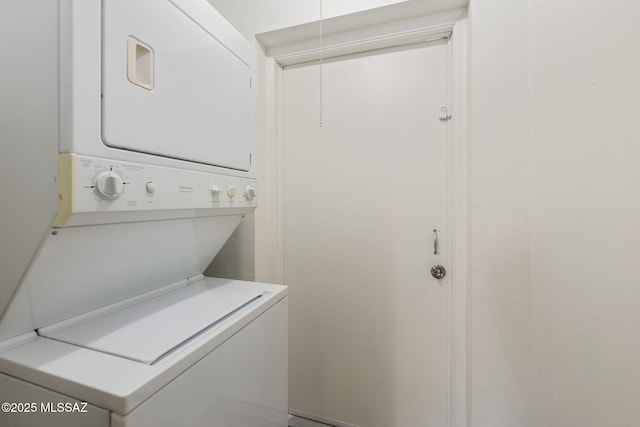 clothes washing area featuring stacked washer and clothes dryer and laundry area