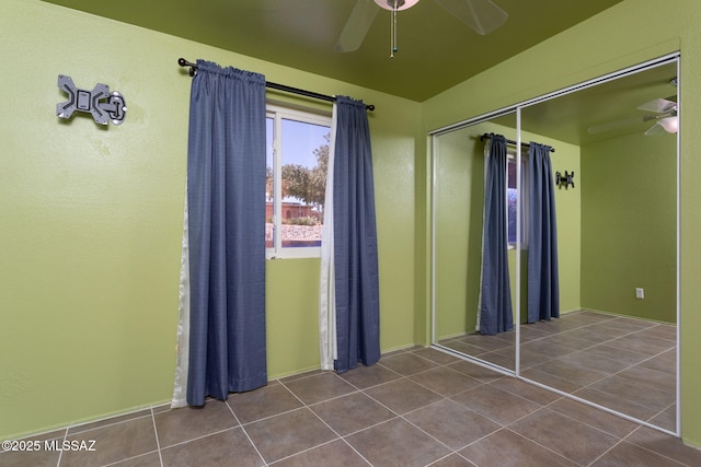 unfurnished bedroom featuring dark tile patterned floors, ceiling fan, and a closet